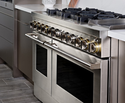 A kitchen with a JennAir Double Oven. On the counter is a potted plant and two cutting boards. There's also a JennAir Wall Oven and a JennAir Built-In Microwave.